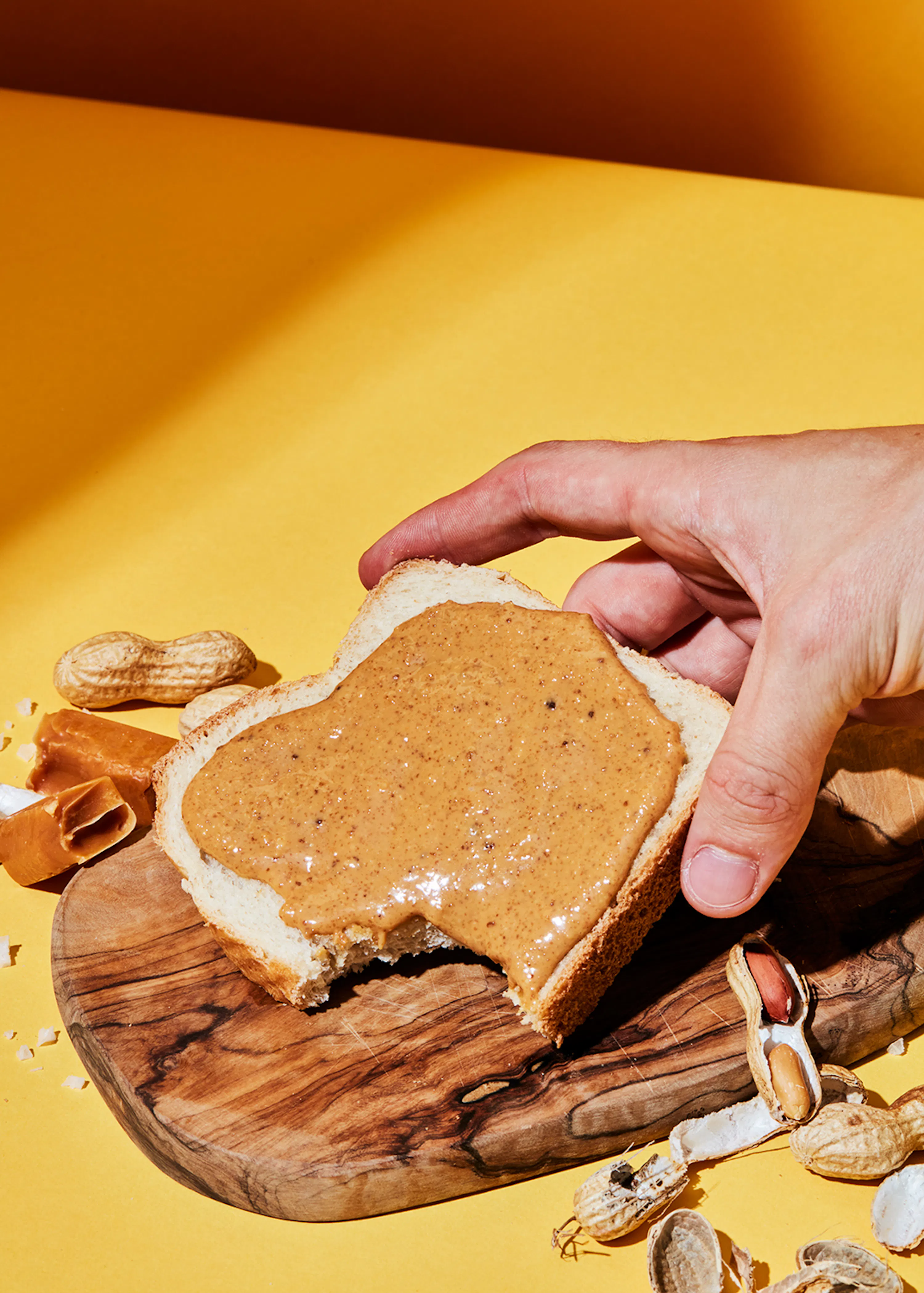 eine Person legt Erdnussbutter auf ein Stück Brot